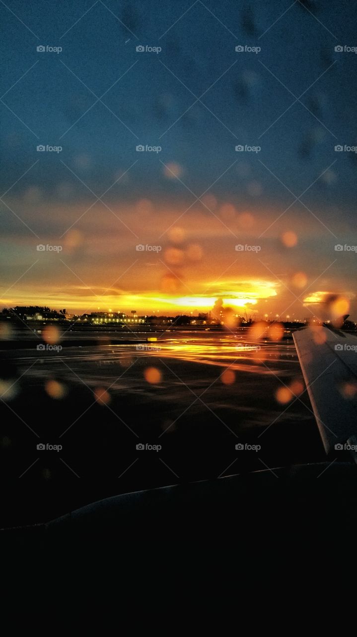 sunrise in the rain. the sunrise shines bright through the raindrops on the tarmac at the airport