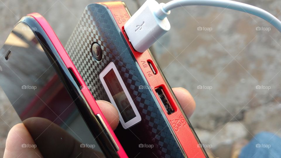 Cabo USB, bateria externa e celular.