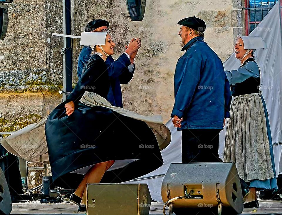 Couples dressed in Breton traditional costumes dancing on stage at the Embroiderers Festival in Pont l'Abbé