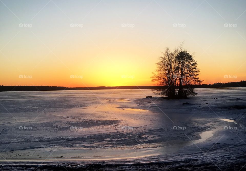 Beautiful winter sunset leaves behind wonderful colors to the sky and icy lake. 