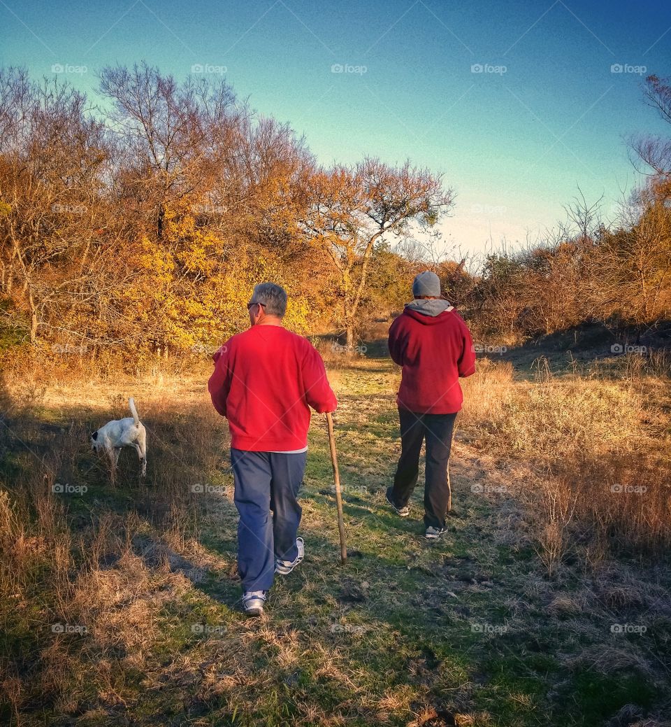 Teo men and their dog taking a hike in early fall