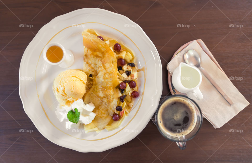 Top view of breakfast with crepe, fruits and coffee