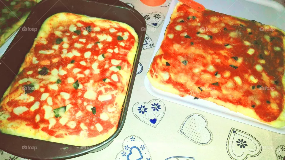 Two homemade margherita pizzas in their baking trays