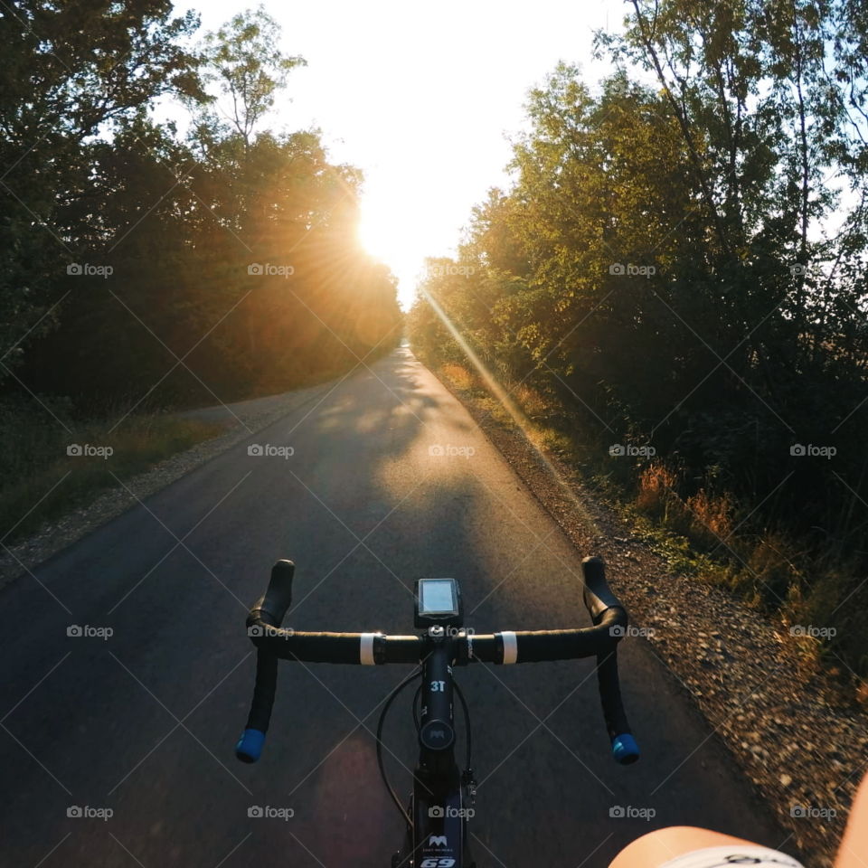 Morning ride with my roadbike on a street towards the sun. Travel by bike to stay healthy. Sunrise makes you think positive. Roadbike cyclist.