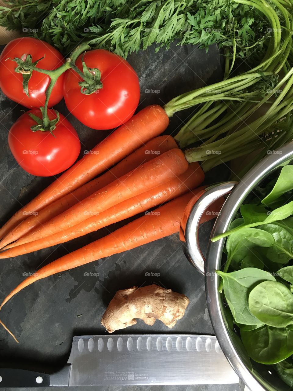 Cooking with fresh vegetables; tomatoes, baby spinach, organic carrots, ginger root. Healthy spring time meals.