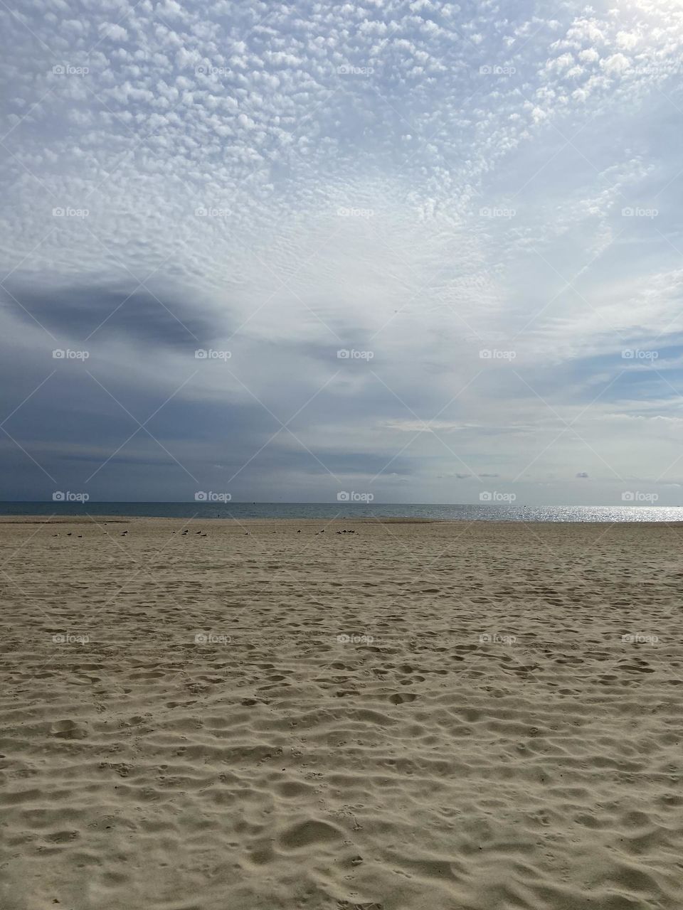 A cloud-filled sky above a sliver of sparkling blue ocean and a sandy beach marked with footprints from beach-goers past. The beach is pretty deserted on this recent September morning, except for some seagulls. The quiet beauty is breathtaking. 