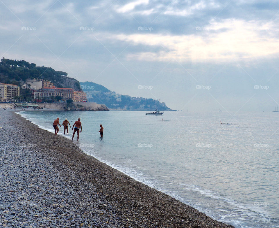 Elderly men playing with a ball on the pebble beach in Nice, France on an early fall morning.