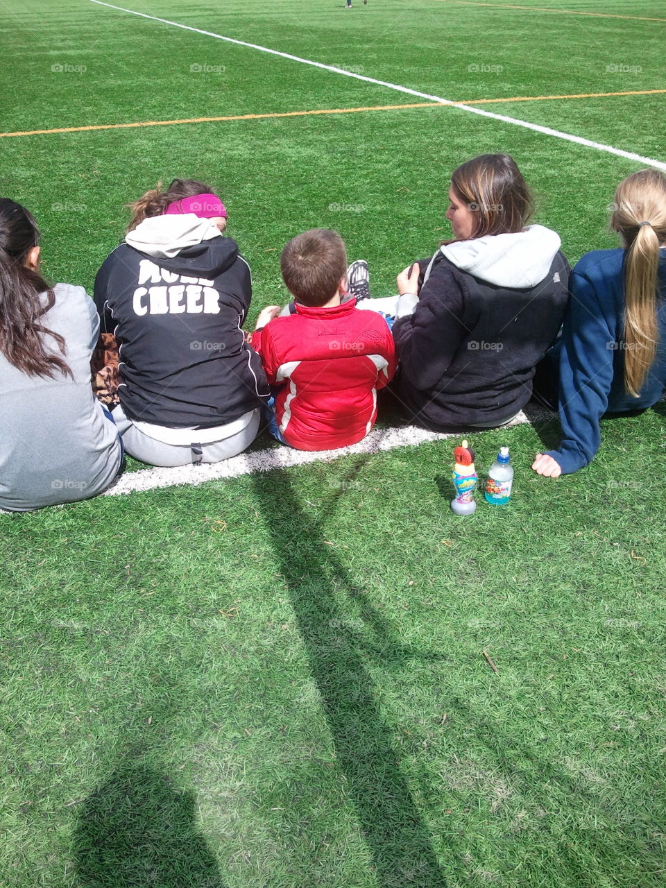 One of the team. Little brother sitting with the team watching his big sister play soccer.