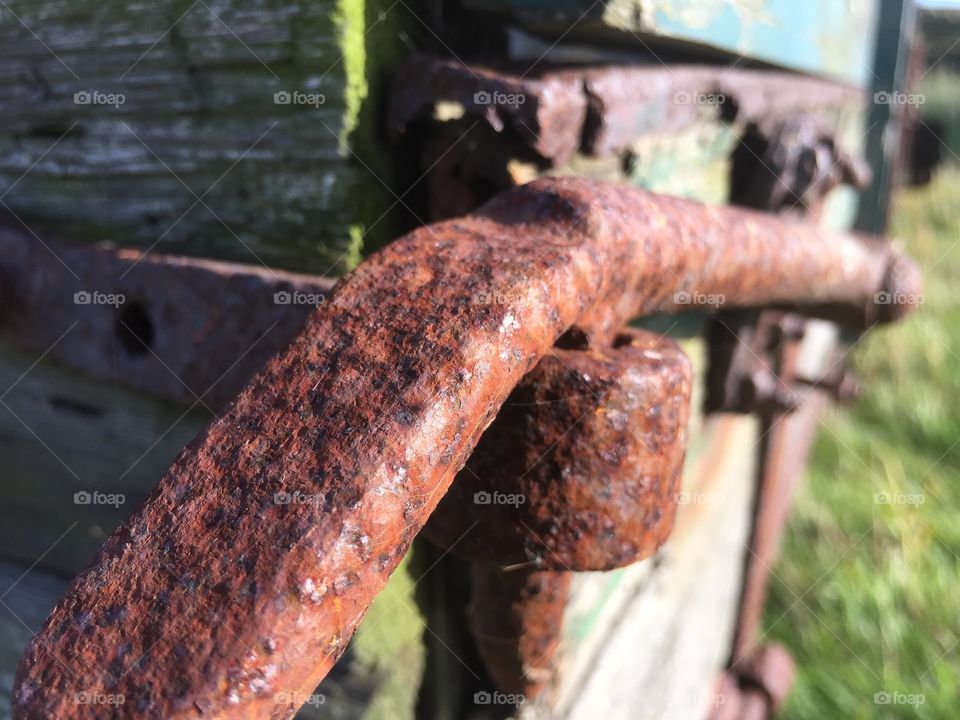 A closeup of a rusty hinge on an old farm wagon 