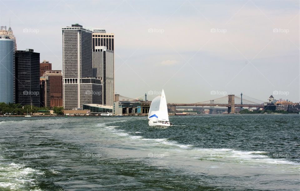 New York City Harbor with a Bridge in the distance and a sailboat close up.