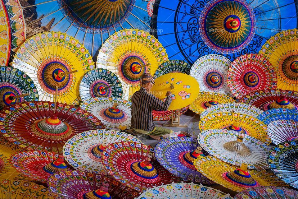 Guardian of Tradition: An aged figure painting a traditional paper umbrella, conserve the wisdom of generations