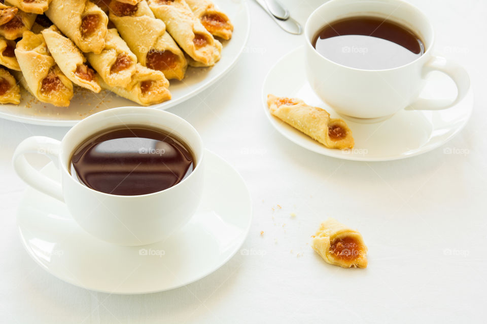 Tea time with Polish cream cheese cookies (Kolacky) with apple jam on white table cloth
