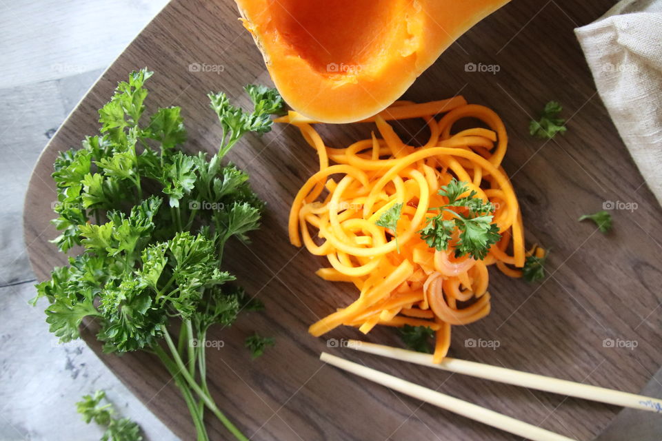 Fresh green parsley and bright orange butternut squash on plate with chopsticks 