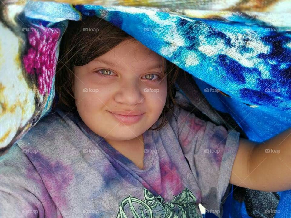 Girl lying in bed under a colorful blanket