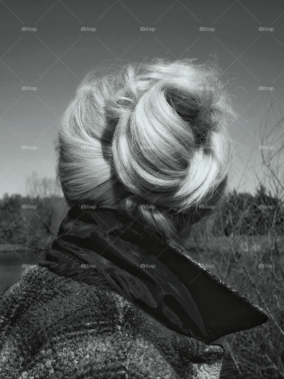 Woman with her hair pulled up in nature from behind in black & white