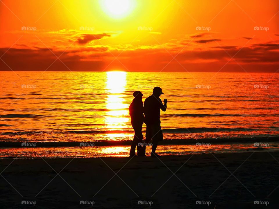 A couple walking on Fort Myers Beach and enjoying the sunset