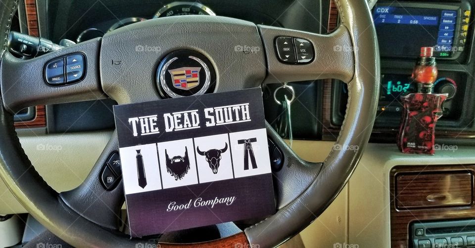 The Dead South cd on the steering wheel of a Cadillac Escalade with a vape (Smok Mag kit) in the background