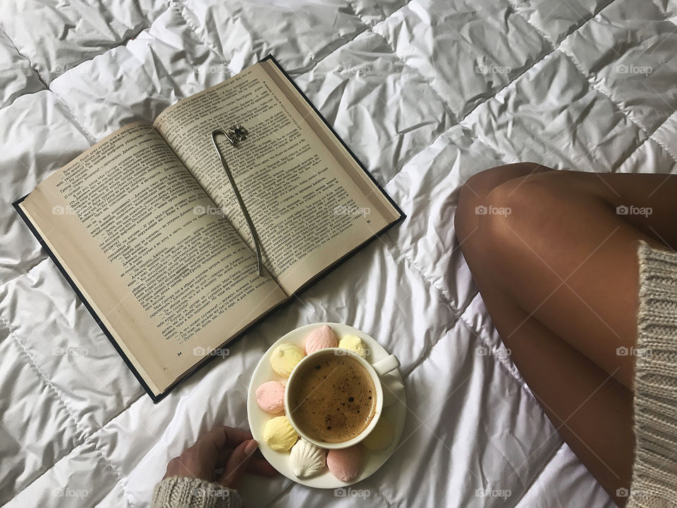 Reading a book with a cup of coffee in bed 