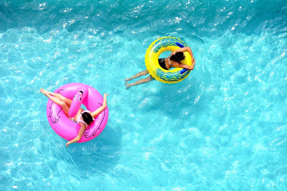 People enjoying a refreshing float in a cool blue swimming pool. 