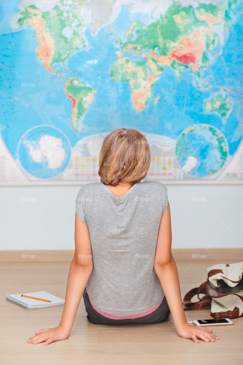 Rear view of a girl sitting in front of world map