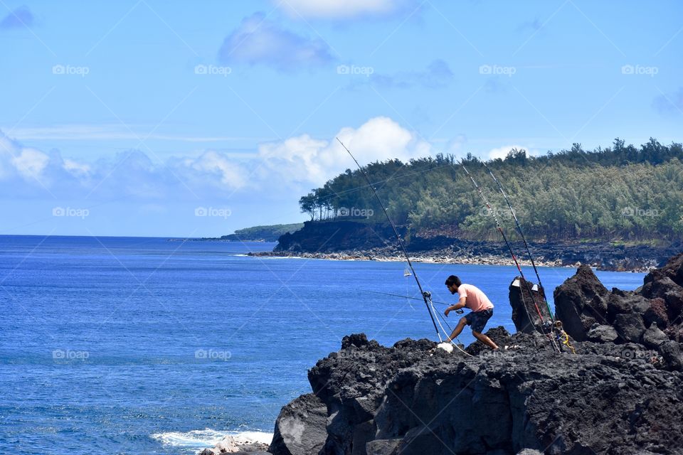 Fishing along the beautiful ocean sea cliffs of lava rock on the east side of the Big Island of Hawaii.