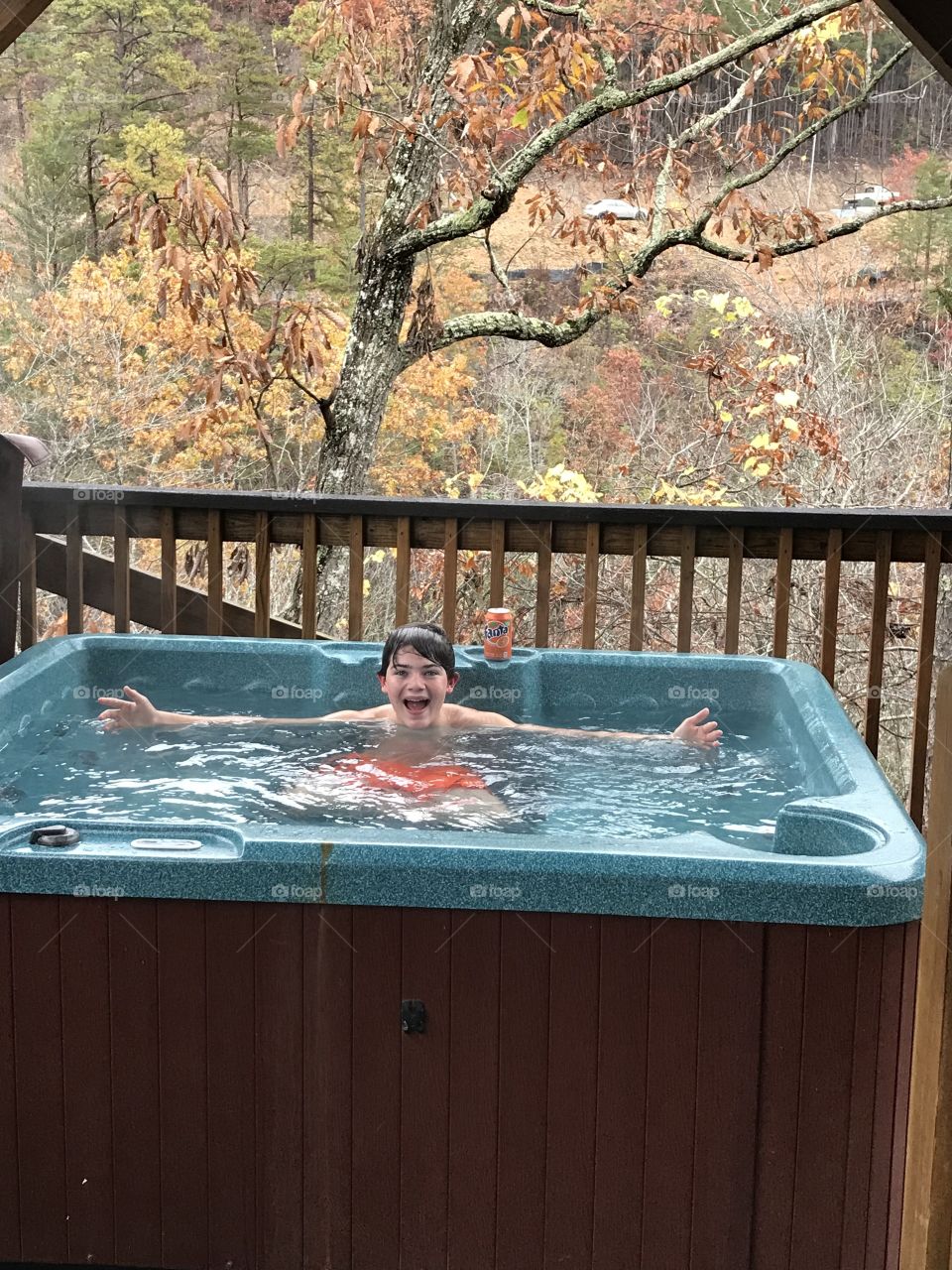 A teen boy on vacation in the Fall in Gatlinburg, Tennessee enjoying a hot tub and a Fanta. 