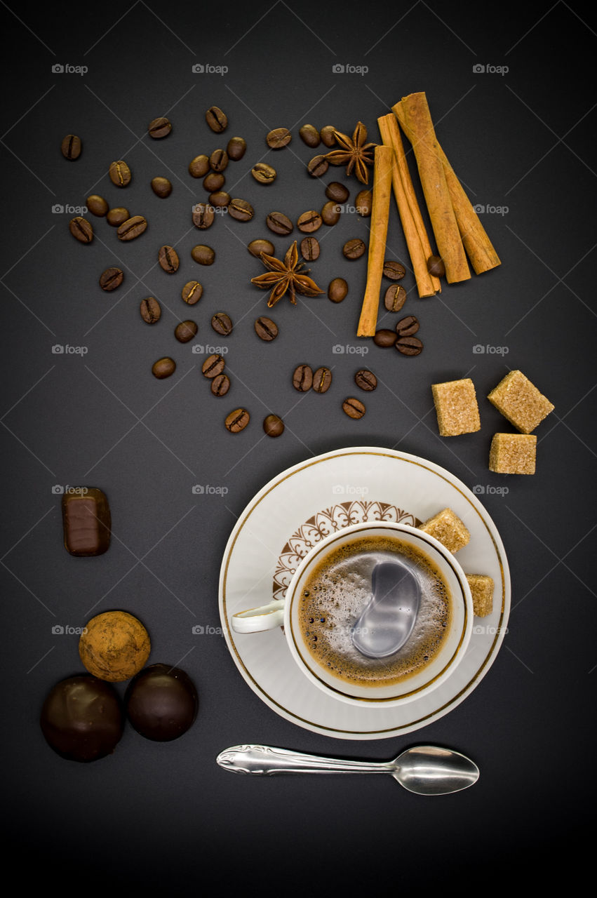 cup of coffee, sweets and different ingredients in plates stand on a black background
