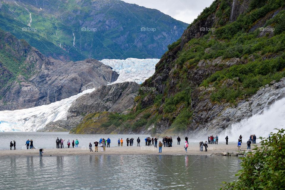 Tourists are dwarfed by the magnitude of the mountain and of the Mendenhall Glacier in the background
