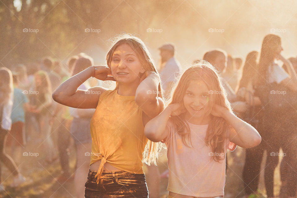 Portrait of happy smiling young girls with colorful paints on faces and clothes. Two friends spending time on holi color festival