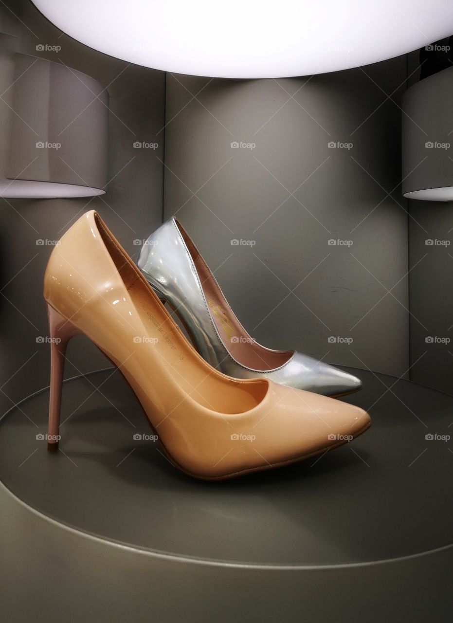 Silver and golden high heels on minimalistic display