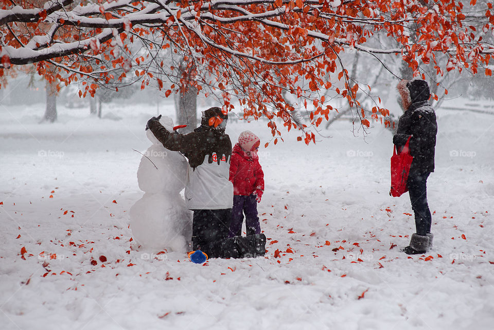 Family build snowman in city park