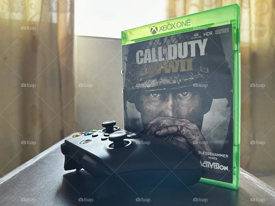 Call of duty video game box behind of a Xbox controller with natural light at the background.