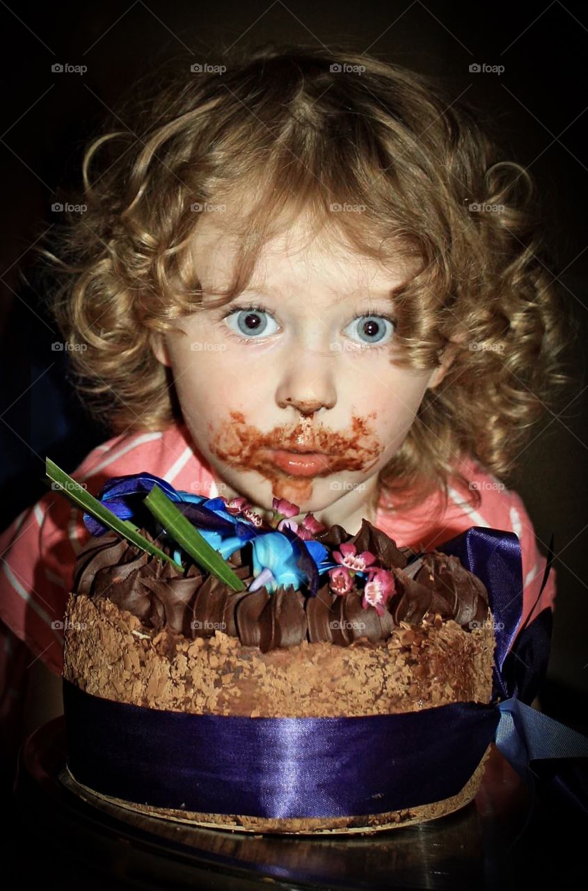 Girl puts her face into birthday cake
