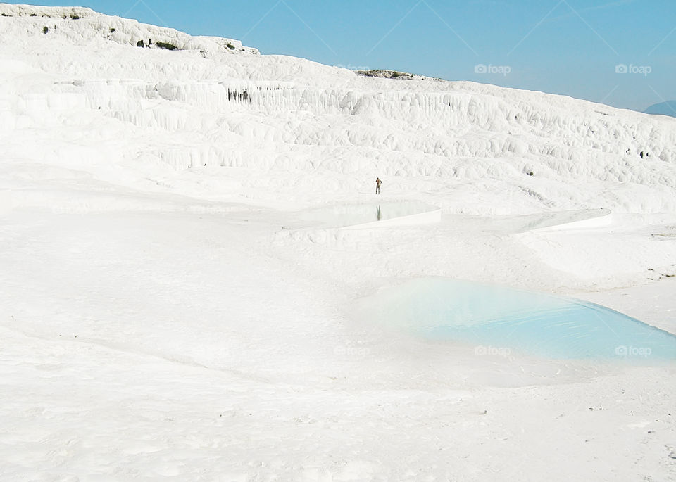 Tiny human among the white chalk mountains in Pamukkale