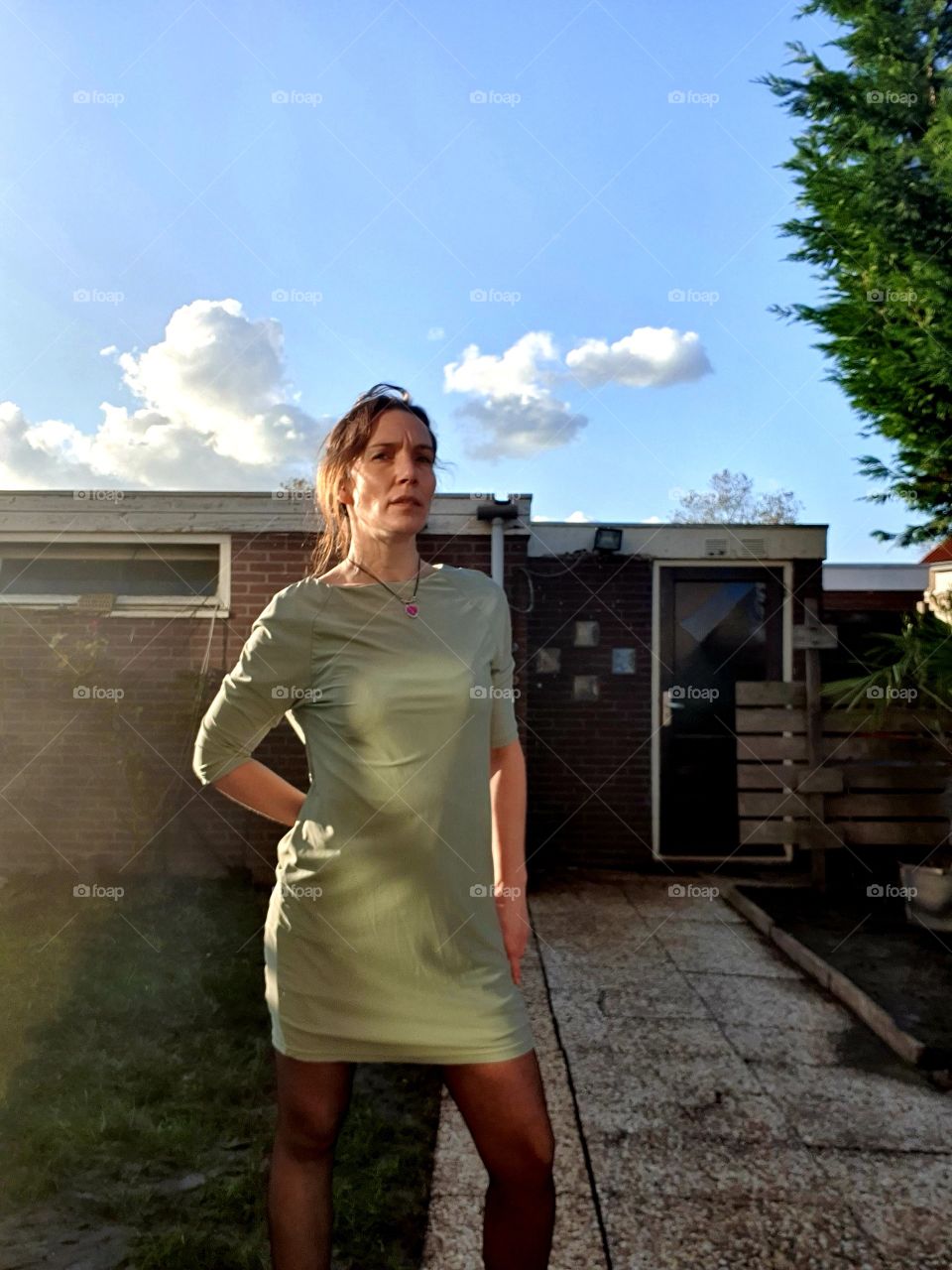 The sun is rising.  Woman in backyard