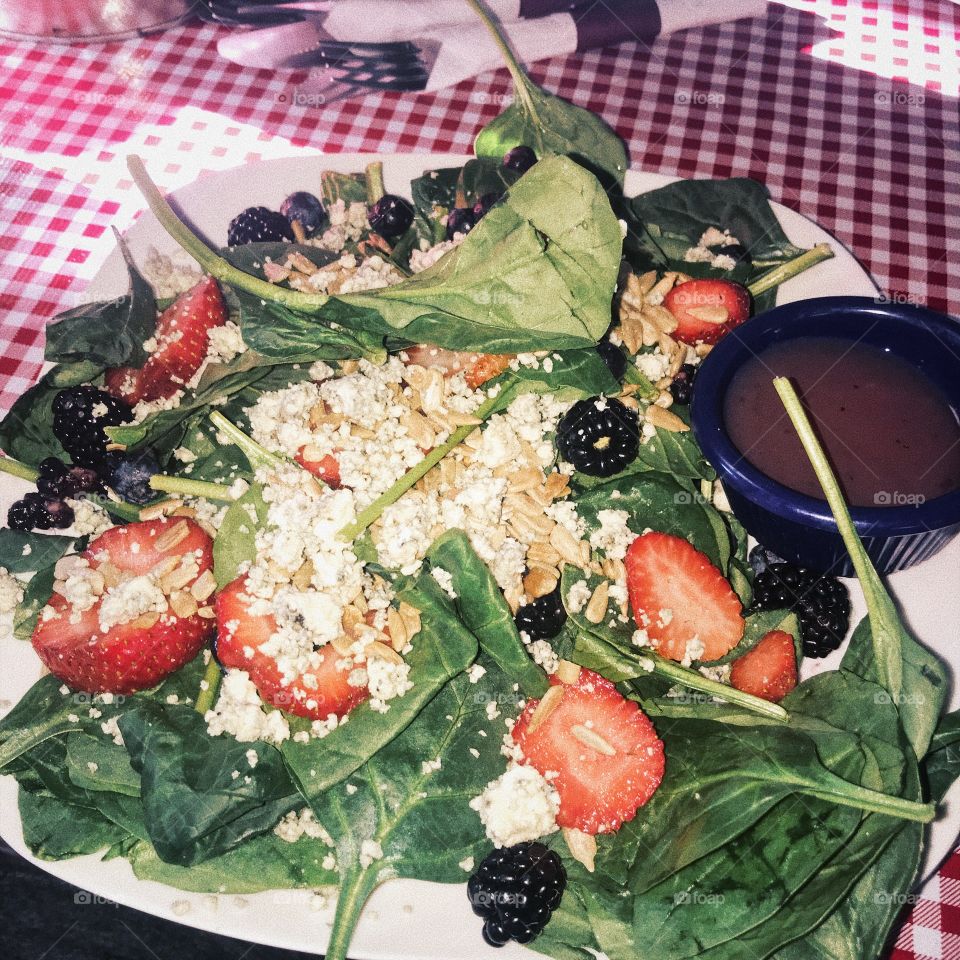 Beautiful garden salad with spinach, fruits, blue cheese, and nuts.