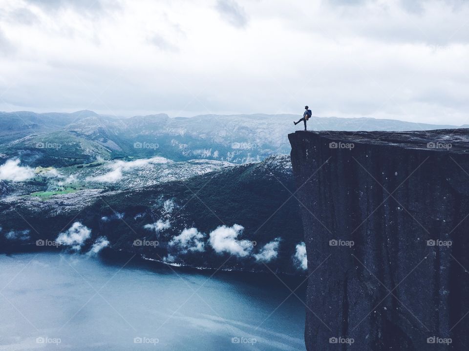 Silhouette stepping from the top of Prekestolen rock. 