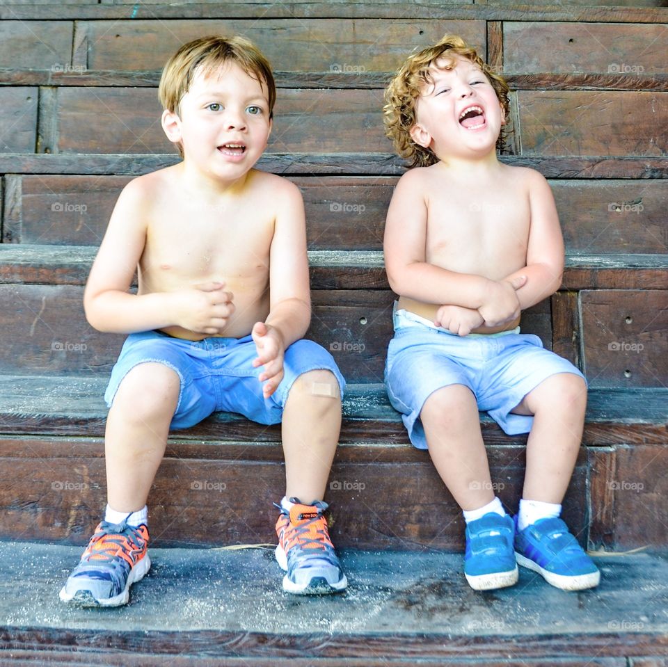 Shirtless boy's sitting on wooden staircase