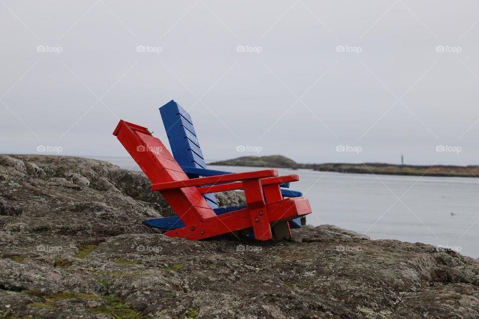 Empty chairs on rocks by the ocean 