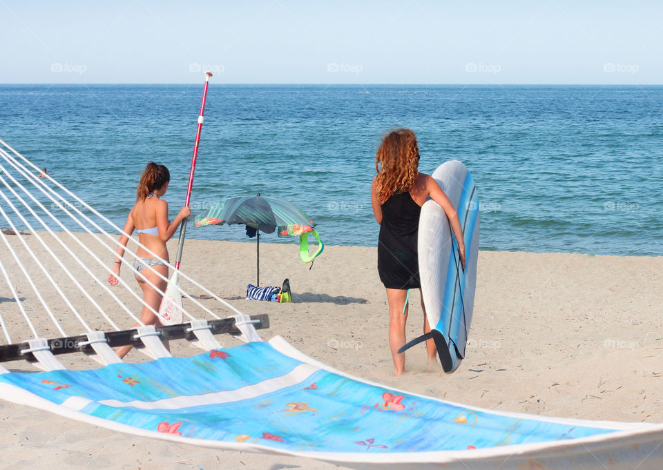 Summer vacation at the beach, women and a surf board