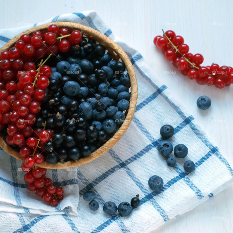 Red currant and blueberries in bowl on white background