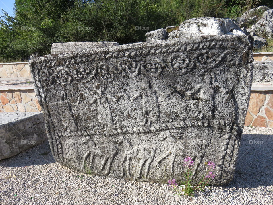 Medieval stone slab with carvings of people dancing and hunting