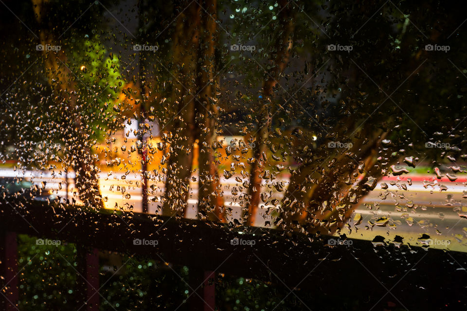 Wet window after rain at the night with car’s lights 