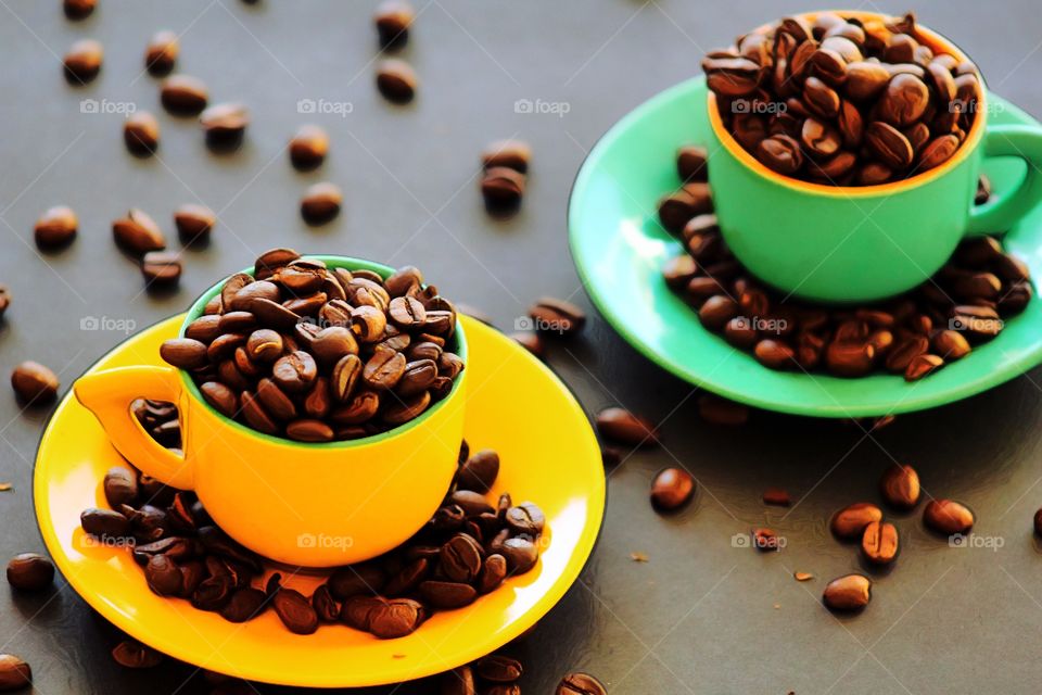 Colorful cups with coffee beans filled