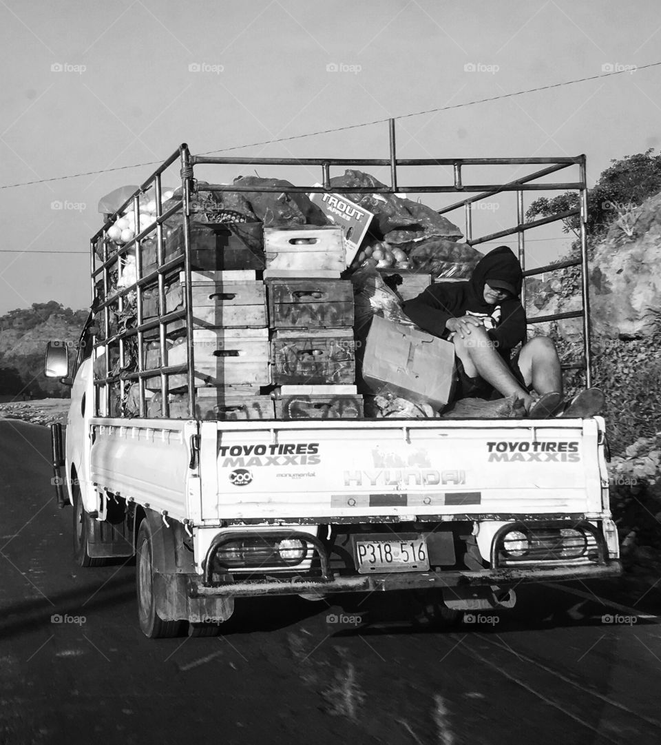 Man sleeping on pickup truck black and white