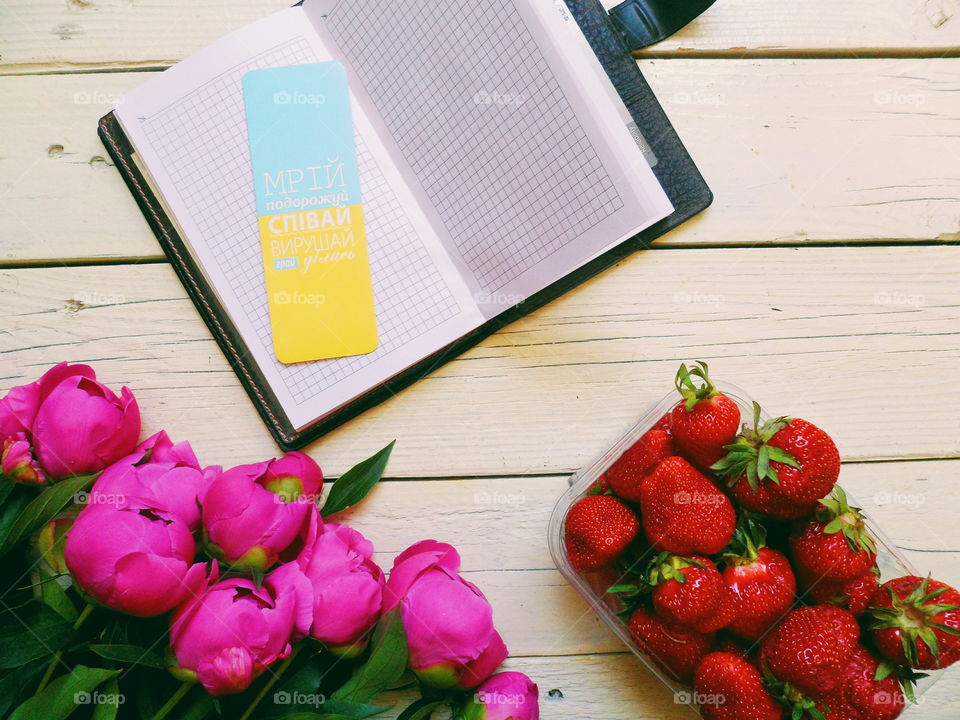 pink peony flowers, strawberry berries and notebook on a white background