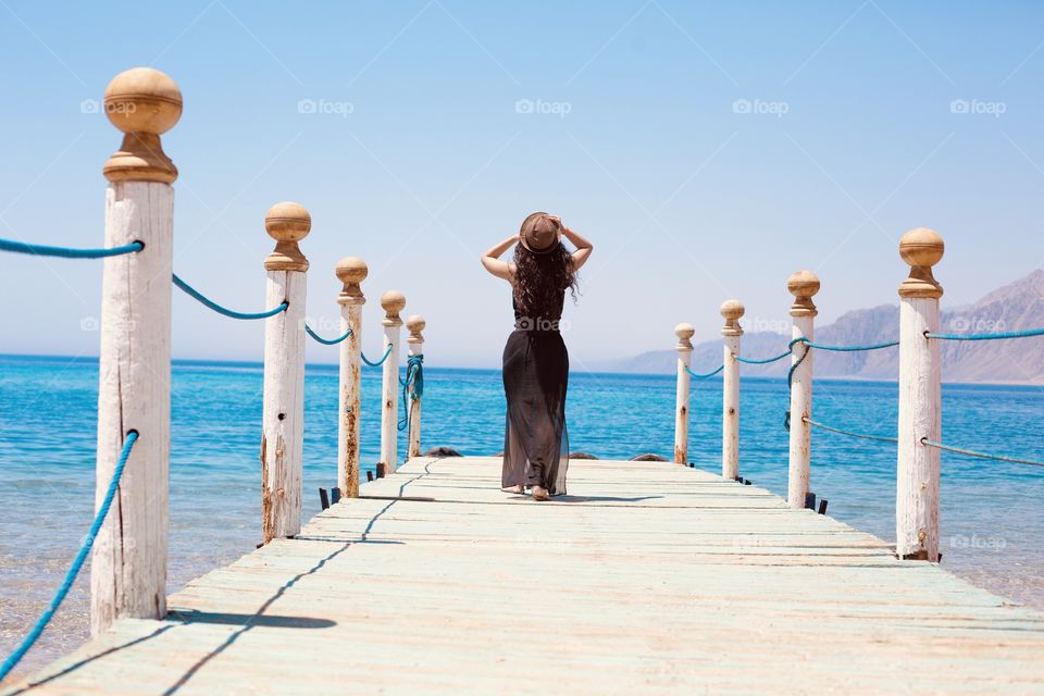 Girl walk in wooden pier with sea view, vacation summer mode 