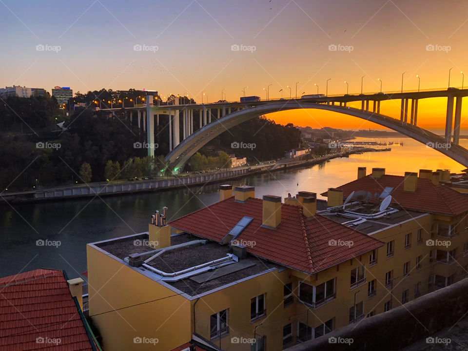 Ponte de Arrábida bridge crosses the Douro River estuary at sunset, with buildings that match the early evening sky in the foreground in Porto - Oct 2019