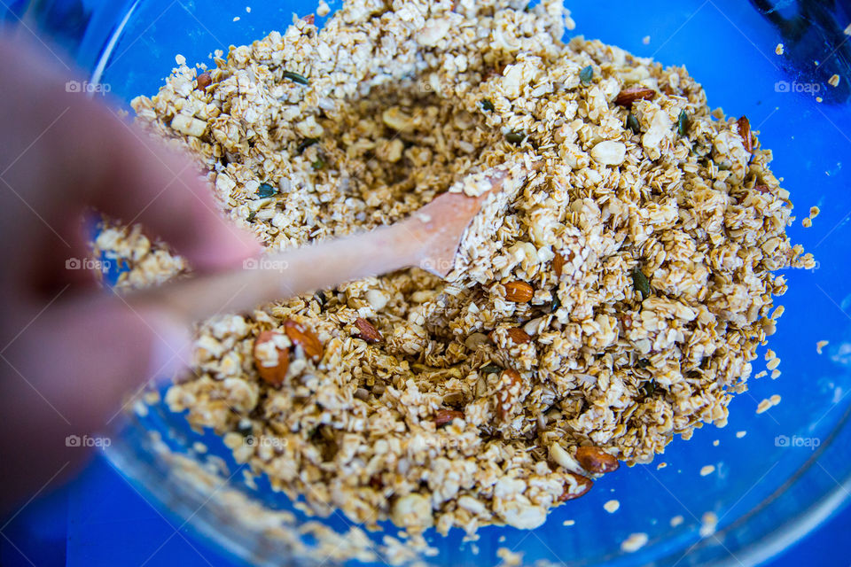 Making and baking at home - woman stirring gronola bake with wooden spoon