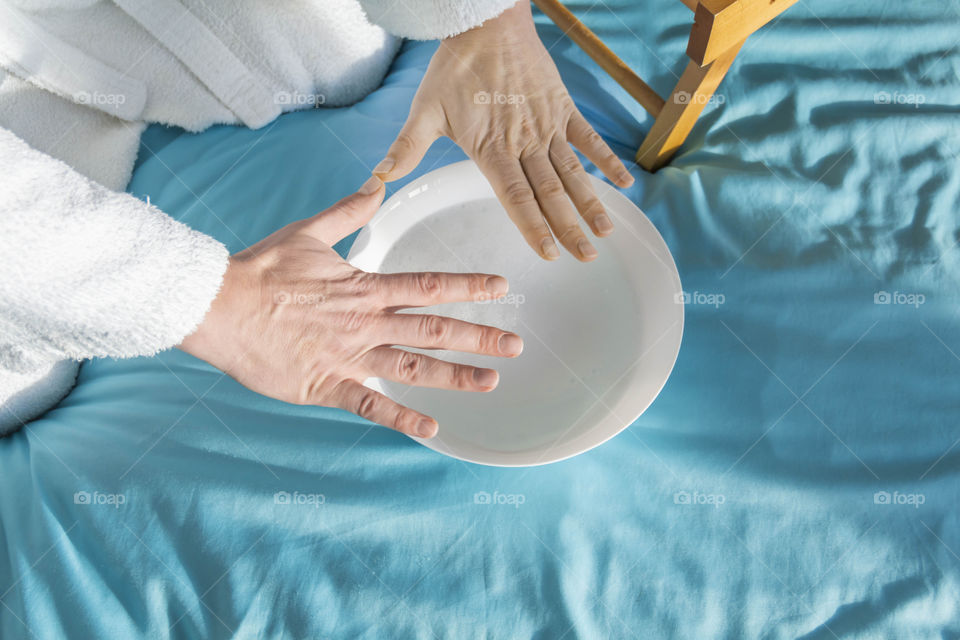 A man at home takes care of himself and does a manicure at home on a blue background and with orange.